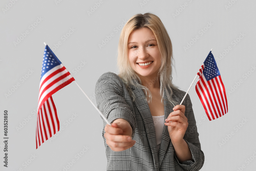 Young businesswoman with USA flags on grey background