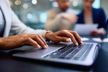 Close up of black financial advisor working on laptop during meeting with her clients.