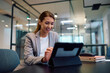 © Drazen - Young happy businesswoman working on digital tablet in office.