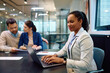 © Drazen - Smiling black real estate agent works on laptop during meeting with her clients in office.