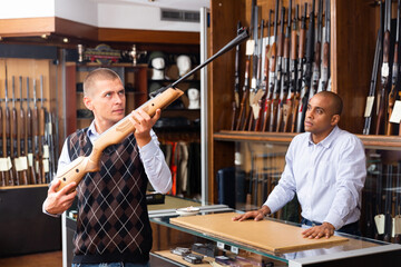 Wall Mural - Guys are choosing pneumatic rifle in airsoft store