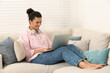 © New Africa - African American woman with laptop on sofa in room