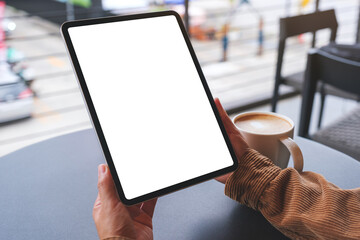 Wall Mural - mockup image of a woman holding digital tablet with blank white desktop screen in cafe