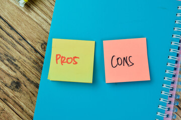 Wall Mural - Concept of Pros or Cons write on sticky notes isolated on Wooden Table.