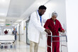 © WavebreakMediaMicro - Diverse male doctor helping senior female patient use walking frame in hospital corridor, copy space