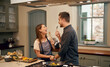 © Tinashe N/peopleimages.com - Love, home and couple in a kitchen, happiness and playful with joy, bonding and loving together. Partners, man and woman with affection, house or singing with humor, relationship or marriage with fun