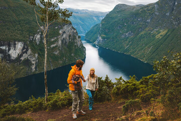 Wall Mural - Family traveling in Norway together hiking above Geiranger fjord Father and mother with infant baby outdoor active healthy lifestyle parents with child tourists in mountains