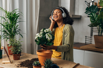 Wall Mural - A beautiful Multiracial woman enjoys working with plants. She listens to music and sings.