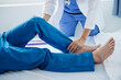 © laddawan - Physiotherapist Helping Patient While Stretching His Leg in bed in clinic .