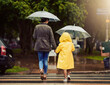 © Arnell K/peopleimages.com - Back, raincoat or umbrella with a mother and daughter walking across a street in the city during winter. Autumn, crosswalk or park with a woman and female child holding hands while crossing a road