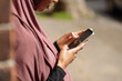 © Connect Images - Young woman in hijab using phone