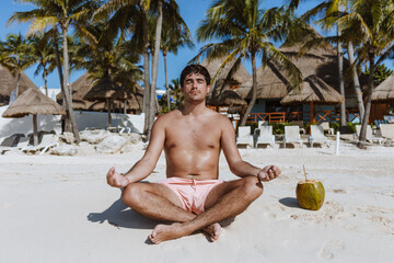 young latin man meditating and relaxation time on the beach in Mexico Latin America, Caribbean and tropical destination 