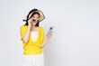 © Thanumporn - Young woman using smart phone and smiling wearing a sun hat and sunglasses isolated on white background.