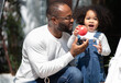 Happy multiracial family having fun at home together. Portrait of multiethnic father and little biracial daughter playing with apple at backyard camping. Diverse ethnic dad laughing with cheerful kid.