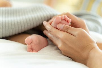 Wall Mural - Mom and Newborn,Happy family concept.Close up view of beautiful Asian mother and her sleeping newborn baby.Mother holding baby hand in one hand and holding hand the baby with eyes closing and smiling.