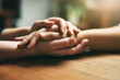 Holding hands, counseling and support of friends, care and empathy together on table after cancer. Kindness, love and women hold hand for hope, trust or prayer, comfort or compassion, help or unity.