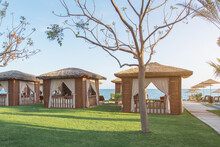 Straw Pavilions On The Beach By The Sea, The Concept Of Rest And Vacation