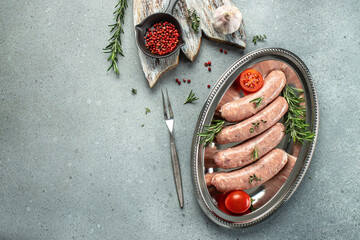 raw butchers sausages in skins with spices, tomatoes and herbs. banner, menu, recipe place for text, top view