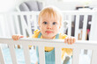 © Austockphoto - baby with wide eyes pulling silly face with lip in cot