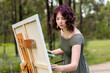 © Austockphoto - Young woman concentrating on painting on canvas