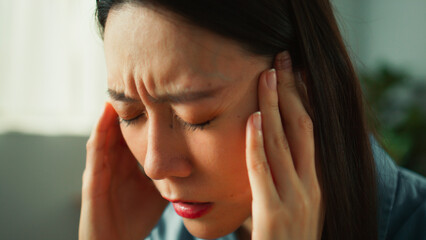 Thoughtful young Asian woman deep thinking on sofa in cozy living room. Female adult looking around bored and tired considering serious plan trying to solve problem in mind, portrait close up concept