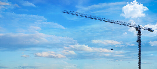 Apartment building construction concept and residential renovation. Copy panoramic area. Construction crane working on building site against blue background .