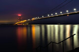 Humber bridge with bright lights across the esturary at pre-dawn. Hessle, UK.
