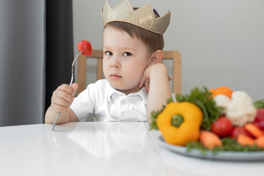 Wall Mural - a sad child holds a tomato on a fork, an unhappy little boy refuses to eat vegetables,  do not like to eat vegetables
