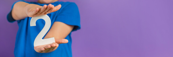 Fototapete - White number 2 in hand. The hand holding the number 2 symbolizes choice, partnership and duality, the choice between two alternatives, to combine the efforts of two people to achieve a common goal.