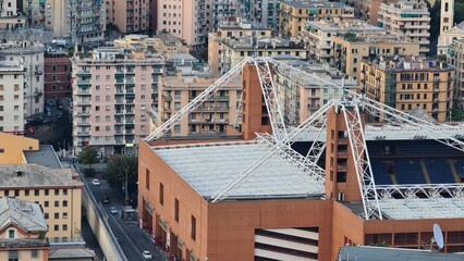 Wall Mural - Genoa, Italy - May 6, 2023: Top view of the city of Genoa at sunset from the mountains. Aerial view of Genoa and Sampdoria soccer teams stadium in Genoa Marassi in Italy.