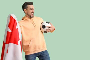 Handsome man with flag of Canada and soccer ball on green background