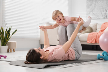 Wall Mural - Mother doing exercise with her daughter at home