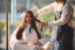 © chokniti - Asian Hairdresser giving treatment and barber occupation service, Professional hairstylist combing and using scissors cut woman's hair to young beautiful customer girl in beauty salon
