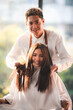 © chokniti - Asian Hairdresser giving treatment and barber occupation service, Professional hairstylist combing and using scissors cut woman's hair to young beautiful customer girl in beauty salon