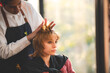© chokniti - Asian Hairdresser giving treatment and barber occupation service, Professional hairstylist combing and using scissors cut woman's hair to young beautiful customer girl in beauty salon