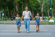 © Pornpimon - Mother and children holding hands cross the road on the crosswalk. Road traffic safety concept.