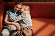 © Clique Images - Horizontal high angle shot of Caucasian woman and her daughter spending time at home relaxing together on couch hugging and smiling