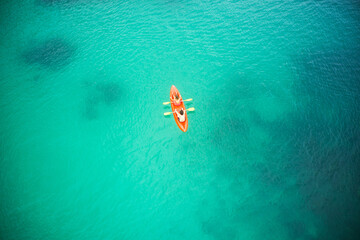 Wall Mural - Top view, boat and people in blue ocean together for kayak adventure, travel or journey at sea on mockup. Couple trailing or rowing on big calm, peaceful or serene beach water in nature for kayaking