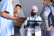 © Wavebreak Media - Diverse male and female doctors holding x-ray and tablets, talking in corridor at hospital