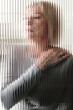 © TrueFrame Collective - Vertical through textured glass wall portrait of elegant senior Caucasian woman with blond bob cut hair, vertical stripes distortion effect