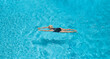 © Ed - View from the height of the flight of a bird, a woman in a swimsuit swims in a blue pool, rests and relaxes