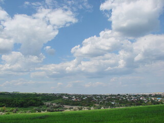 A panorama of cloud patterns in the blue sky above a young rye field on the outskirts of the village.