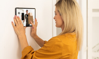 Woman watching delivery man on security camera cctv video on tablet