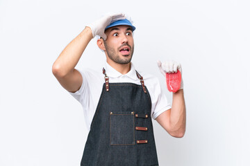 Butcher caucasian man wearing an apron and serving fresh cut meat over isolated white background doing surprise gesture while looking to the side