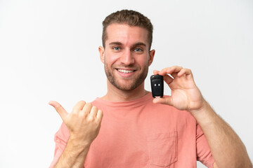 Canvas Print - Young caucasian man holding car keys isolated on white background pointing to the side to present a product