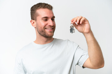 Young caucasian man holding home keys isolated on white background with happy expression