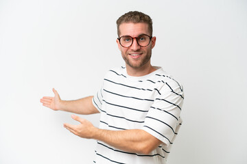 Canvas Print - Young handsome caucasian man isolated on white background extending hands to the side for inviting to come