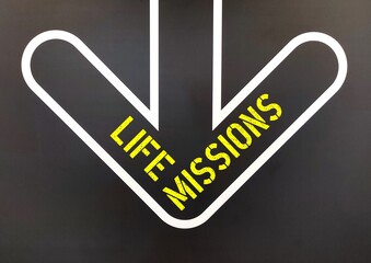 Wall background with inscription text direction sign point to LIFE MISSIONS, means key aspects of life that make worth living to fulfill a goal or passion