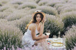 Beautiful young woman having picnic on the lavender field. Healthy food. Fresh fruits. 
