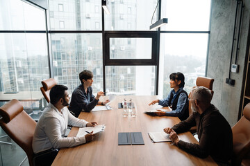 Overhead view of concentrated multiethnic colleagues discussing work project in office